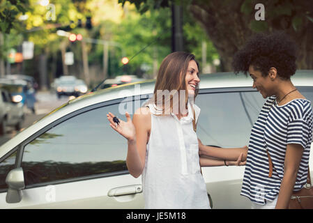 Junge Frau zeigt stolz Freund Schlüssel für neues Auto Stockfoto