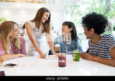 Kellnerin serviert Drinks zu Gruppe von Frauen im café Stockfoto