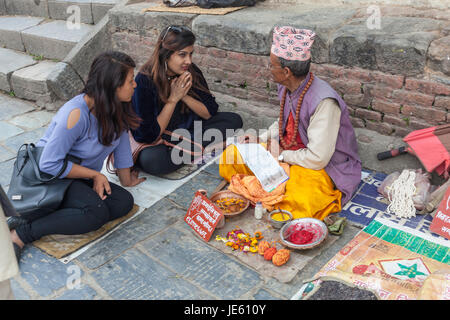 Tibetischen Heiligen Mann oder Priester bietet Beratung und Anleitung, um zwei junge britische Teenager oder weiblich: weiblich im Kathmandu-Tal in Kathmandu Stockfoto