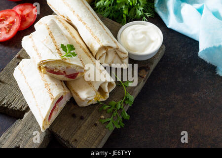 Shaurma Lavash mit gebratenem Hühnerfleisch, frischem Gemüse und Sahnesauce auf einem Hintergrund von braunen Stein. Kopieren Sie Raum. Stockfoto