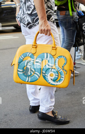 Mailand - 17.Juni: Mann mit mit gelben Gucci-Tasche mit blaue Schlange und weißen Hosen vor Les Hommes Modenschau, Milan Fashion Week Streetstyle auf Stockfoto