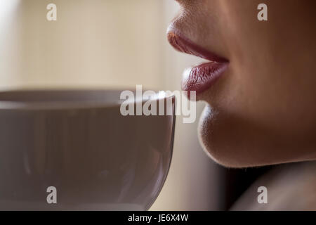 Schuss des Weibes Lippen berühren weiße Tasse Tee oder Kaffee hautnah. Stockfoto