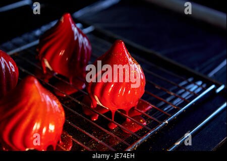 Feuer-Beeren-Kuchen, eine zarte Creme Mousse, bedeckt mit unglaublich glänzenden spiegelnden Glasur auf die Kondensmilch, verbirgt im Inneren Serdtsevinka Lemon Jelly und Ganache ist unglaublich nützlich Oblepiha. Basierte Cupcake knusprige Mandel-Kokos-Köder mit einem Hauch von Ingwer. Unglaubliche Kombination aus Geschmack und Farben in einem Kuchen Stockfoto