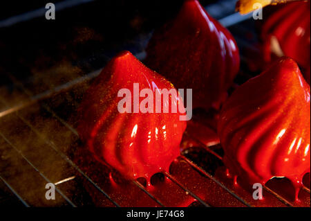 Feuer-Beeren-Kuchen, eine zarte Creme Mousse, bedeckt mit unglaublich glänzenden spiegelnden Glasur auf die Kondensmilch, verbirgt im Inneren Serdtsevinka Lemon Jelly und Ganache ist unglaublich nützlich Oblepiha. Basierte Cupcake knusprige Mandel-Kokos-Köder mit einem Hauch von Ingwer. Unglaubliche Kombination aus Geschmack und Farben in einem Kuchen Stockfoto