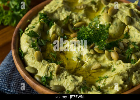 Rohe Bio Avocado Hummus mit Fladenbrot Zitronen und Petersilie Stockfoto