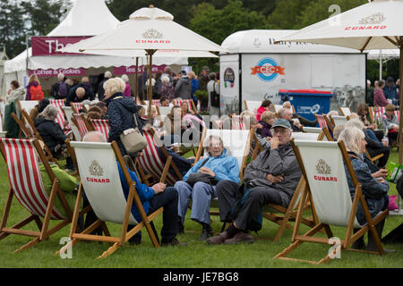 Trotz des kalten Wetters sitzen Menschen in Liegestühlen auf der ersten RHS Chatsworth Flower Show - Chatsworth House, Derbyshire, England, UK. Stockfoto