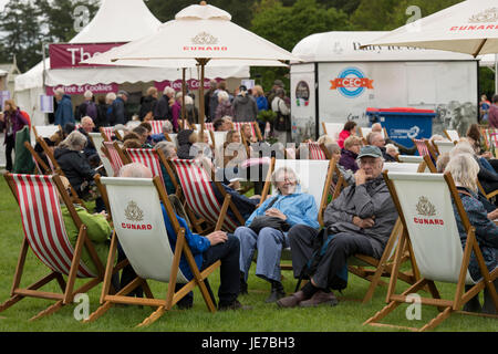 Trotz des kalten Wetters sitzen Menschen in Liegestühlen auf der ersten RHS Chatsworth Flower Show - Chatsworth House, Derbyshire, England, UK. Stockfoto