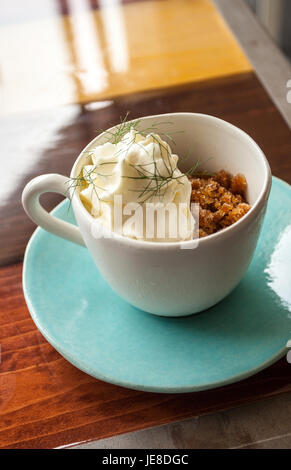 Kaffee Granit mit weißer Schokolade Schaum und wildem Fenchel, in einer blauen Tasse mit Disch, Umgebungslicht. Stockfoto