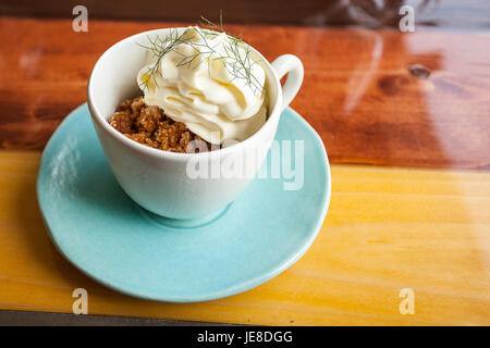 Kaffee Granit mit weißer Schokolade Schaum und wildem Fenchel, in einer blauen Tasse mit Disch, Umgebungslicht. Stockfoto