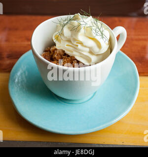 Kaffee Granit mit weißer Schokolade Schaum und wildem Fenchel, in einer blauen Tasse mit Disch, Umgebungslicht. Stockfoto