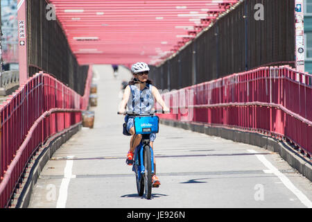 Asiatische Touristen mit dem CitiBike Fahrrad Teilen auf der Williamsburg Bridge, New York City Stockfoto