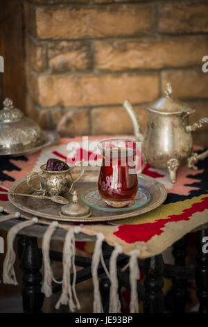 Tee-Set im orientalischen Stil in Birne geformt Glas mit Löffel und Vintage Wasserkocher und Termine Frucht auf silbernen Tablett auf silbernen Tablett gegen Mauer Stockfoto