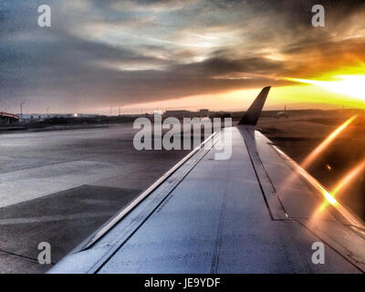 Dieses Bild zeigt einen dramatischen Sonnenuntergang aus dem Flugzeug und zeigt die leuchtenden Farben des Himmels während der Abendstunden. Die Sonnenstrahlen heben die Flügel des Flugzeugs hervor und verleihen der Szene eine einzigartige Perspektive. Stockfoto