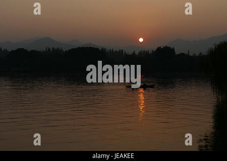 Dieses Bild zeigt einen Sonnenuntergang über dem Westsee (Xihu) in Hangzhou, China, am 21. November 2014. Die malerische Landschaft zeigt das ruhige Wasser des Sees mit leuchtenden Farben des Sonnenuntergangs, die sich auf seiner Oberfläche spiegeln. Stockfoto
