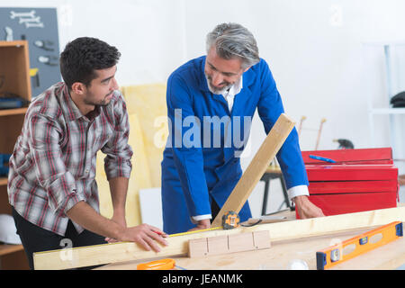 Tischler und Assistent arbeiten Holz in Werkstatt Stockfoto