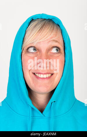 Schöne europäische Mitte Alter Frau mit blonden Haaren, gekleidet in eine leichte blaue Lässige Kapuzenjacke - Studio erschossen vor einem weißen Hintergrund Stockfoto