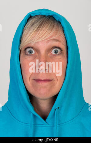 Schöne europäische Mitte Alter Frau mit blonden Haaren, gekleidet in eine leichte blaue Lässige Kapuzenjacke - Studio erschossen vor einem weißen Hintergrund Stockfoto