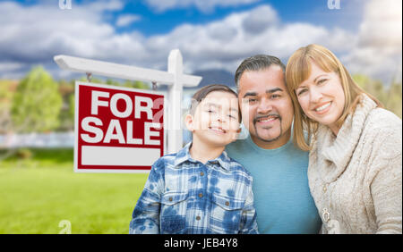 Gemischte Rassen Familienporträt vor Haus und Immobilien Verkaufsschild Stockfoto