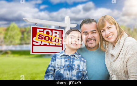 Gemischte Rassen Familie vor der Haus und verkauft für Immobilien Verkaufsschild Stockfoto