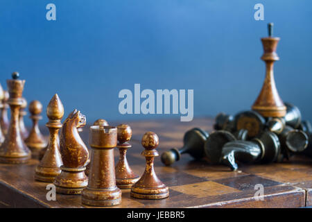 Alte hölzerne Schachfiguren auf einem alten Schachbrett. Auf einem blauen Hintergrund. Stockfoto