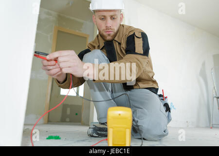 Techniker, die mit einem digitalen Multimeter Messspannung eines Sockets Stockfoto