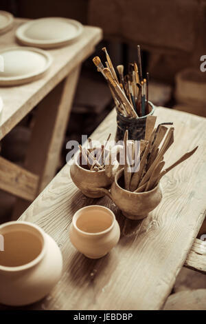 Nahaufnahme von Pinseln mit Keramik-Tools in Schalen auf Tisch Stockfoto