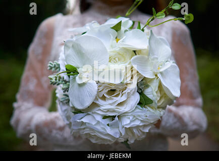 Asiatische Frau tragen weiße geschnürt Brautkleid Holding weißer Blumenstrauß vor ihr in einem abgelegenen Ort in der wunderschönen Saryeoni-Supgil Park in Jeju Stockfoto