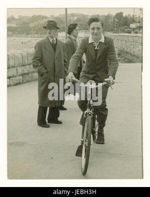 Originale nostalgische Originalfotos von einem glücklichen, sorgenfreien Teenager auf seinem Fahrrad an der Torquay Promenade - einer typischen britischen Küstenstadt, möglicherweise im Urlaub, 1940er, Torquay, Devon, GROSSBRITANNIEN Stockfoto