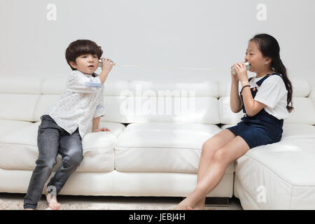 Asiatische chinesische kleinen Bruder und Schwester spielen Blechdose Telefon im Wohnzimmer zu Hause. Stockfoto