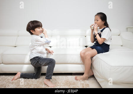 Asiatische chinesische kleinen Bruder und Schwester spielen Blechdose Telefon im Wohnzimmer zu Hause. Stockfoto