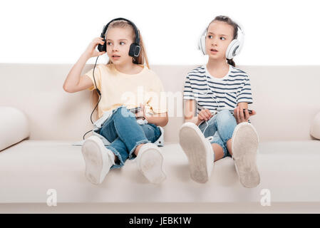 Niedlichen Mädchen mit Smartphones, hören Musik auf couch Stockfoto