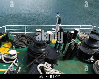 Arbeitnehmer auf Schiff wicklung in Festmacher Seile bereit, Abk. dock Linien um den Hafen verlassen Stockfoto