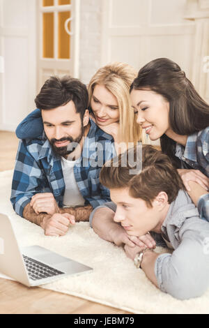 Zwei junge Paare am Boden liegend, Spaß haben und mit laptop Stockfoto