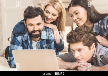Zwei junge Paare am Boden liegend, Spaß haben und mit laptop Stockfoto