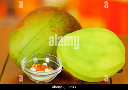 Aufnahme von raw und geschälte Mango hinter einer Salz und Chili-Pulver-Schüssel hautnah Stockfoto