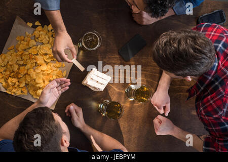 junge Männer Bier trinken und Jenga-Spiel zu spielen. junge Leute, die Spaß Konzept Stockfoto
