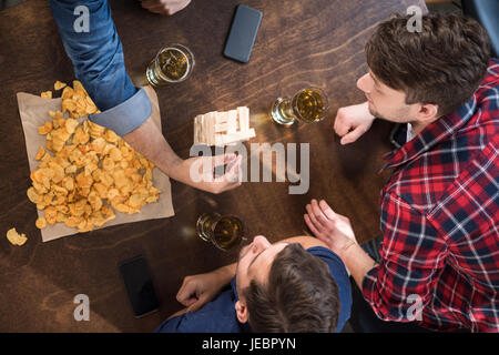 junge Männer Bier trinken und Jenga-Spiel zu spielen. junge Leute, die Spaß Konzept Stockfoto