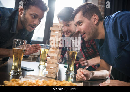 junge Männer Bier trinken und Jenga-Spiel zu spielen. junge Leute, die Spaß Konzept Stockfoto
