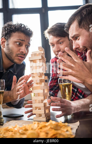 junge Männer Bier trinken und Jenga-Spiel zu spielen. junge Leute, die Spaß Konzept Stockfoto