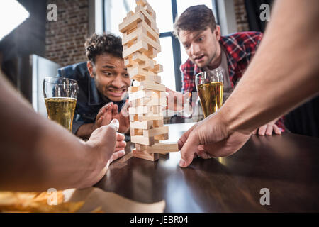 junge Männer Bier trinken und Jenga-Spiel zu spielen. junge Leute, die Spaß Konzept Stockfoto