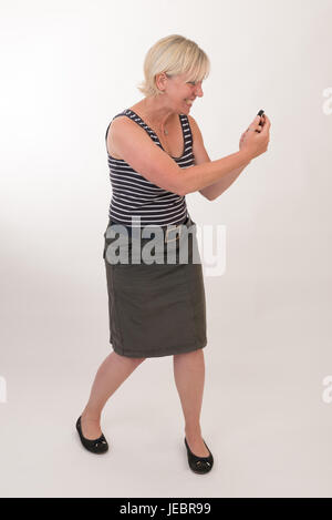 Porträt von einer attraktiven Blondine Rothaarige Mitte Alter Europäerin tragen Blau gestreiftes Top Schauspiel mit Mobiltelefon - Studio gedreht auf weißem Hintergrund. Stockfoto