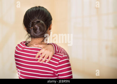 Junge lateinamerikanische Frau posiert für die Kamera zeigt Anzeichen von Schmerzen in der Schulter, Hand in Hand auf schmerzhafte Körperteil, Verletzungen Konzept. Stockfoto