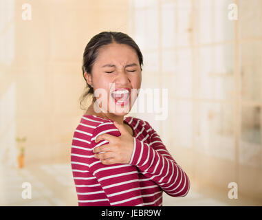 Junge lateinamerikanische Frau posiert für die Kamera zeigt Anzeichen von Schmerzen in der Schulter, Hand in Hand auf schmerzhafte Körperteil, Verletzungen Konzept. Stockfoto