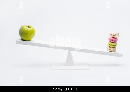 Nahaufnahme von Apple und Macarons balancieren auf Wippe, gesundes Wohnkonzept Stockfoto