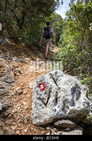 Eine Frau, eine steile beschilderten Weg hinauf auf die Insel Mljet-Kroatien-Überschrift für die Gipfel des Veliki Skladin und Montokuc im Nationalpark Stockfoto