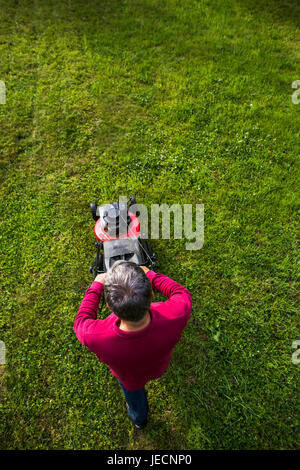 Senior woman Mähen des Rasens in seinem Garten Stockfoto