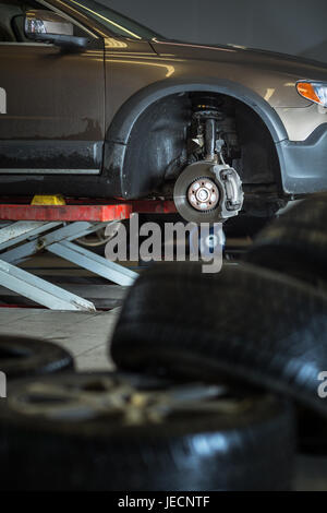 In einer Garage - modernes Auto wartet der Mechaniker seine Räder/Reifen (flachen DOF; getönten Farbbild) ändern Stockfoto