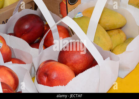 Bio-Äpfeln und Mangos in weißen Papiertüten auf Bauernmarkt Stockfoto