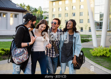 Vier jung und glücklich Studenten auf dem Campus zu Fuß und einige Universität Probleme zu diskutieren. Stockfoto