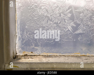 Frost auf dem Glas von einem alten Holzfenster in einer Berghütte Stockfoto